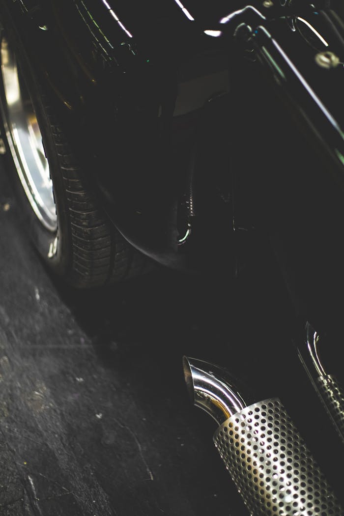services-02 Detailed view of a vintage car's shiny chrome exhaust and tire reflecting ambient light.