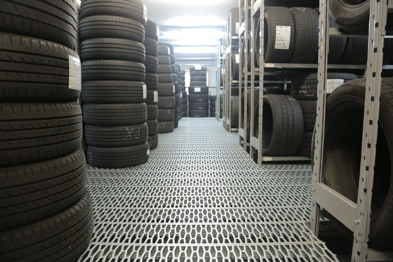services-01 Rows of stacked tires in an indoor industrial warehouse for storage.
